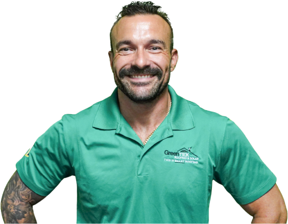 A man with short hair and a beard smiles at the camera, wearing a green polo shirt with "GreenTEX" and "ROOFING & SOLAR" written on it—proudly representing roofing Tampa. He stands with one arm on his hip, showing tattoos on his left arm.