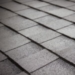 Close-up view of gray asphalt roof shingles arranged in overlapping rows, creating a textured and uniform pattern.