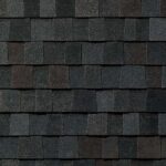 Close-up view of dark gray and black asphalt roof shingles arranged in a neat, overlapping pattern, showing texture and subtle color variations.