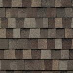 Close-up view of a roof with overlapping rectangular asphalt shingles in various shades of brown and gray, forming a repeating, textured pattern.