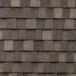 Close-up view of brown asphalt shingles on a roof, arranged in an overlapping pattern with subtle variations in color and texture.