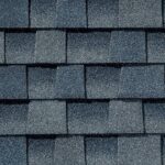 Close-up of blue-gray asphalt shingles arranged in a staggered pattern, showing textured, granulated surfaces and subtle color variations.