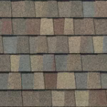 Close-up view of multi-colored asphalt roof shingles arranged in horizontal rows, featuring a mix of gray, tan, and brown shades with a textured surface.