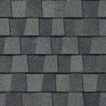 Gray asphalt roof shingles arranged in a staggered pattern, showing varied shades of gray and a textured, granular surface.