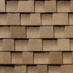 Close-up view of overlapping brown asphalt roof shingles arranged in a staggered pattern, showing texture and detail.