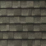 Close-up view of dark gray asphalt shingles arranged in horizontal rows on a roof, showing the textured surface and overlapping pattern of the roofing material.
