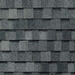 Gray asphalt roof shingles arranged in an overlapping, horizontal pattern, creating a textured surface typical of residential roofing.