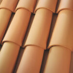 Close-up of overlapping terracotta roof tiles arranged in neat, horizontal rows, showing their curved shape and smooth, reddish-brown surfaces.
