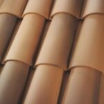 Close-up view of overlapping curved terracotta roof tiles arranged in neat rows, with varying shades of brown and tan.
