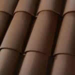 Close-up view of overlapping brown ceramic roof tiles arranged in rows, showing their smooth texture and curved shape.