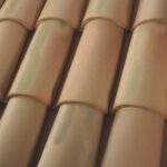 Close-up view of overlapping, curved terracotta roof tiles arranged in neat, horizontal rows, showing their smooth, light brown surface and subtle shading.