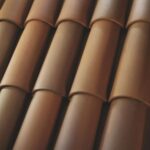 Close-up view of overlapping brown ceramic roof tiles arranged in neat, parallel rows. The tiles have a smooth texture and subtle color variations.