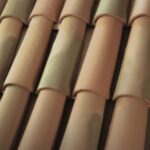 Close-up view of reddish-brown clay roof tiles arranged in overlapping rows with a slightly weathered appearance.