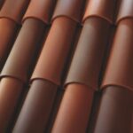 Close-up of overlapping terracotta roof tiles arranged in neat, parallel rows, showing varying shades of reddish-brown and smooth, curved surfaces.