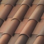 Close-up of a roof with overlapping rows of curved, reddish-brown clay tiles arranged in a diagonal pattern.