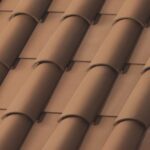 Close-up of brown ceramic roof tiles arranged in a neat, overlapping pattern, creating a wavy, textured surface typical of traditional roofing.