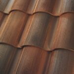 Close-up view of overlapping, curved terracotta roof tiles with a textured, ridged surface and varying shades of brown and orange.