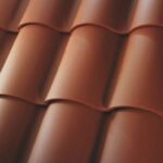 Close-up view of red terracotta roof tiles arranged in overlapping rows, creating a wavy pattern. The tiles have a smooth texture and a matte finish.