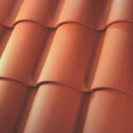 Close-up of orange-red clay roof tiles arranged in overlapping rows, creating a wavy, textured pattern.