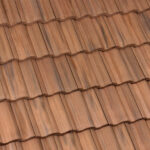 Close-up view of brown, overlapping clay roof tiles arranged in neat, horizontal rows, creating a textured pattern on a rooftop.