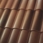 Close-up of brown, overlapping, wavy roof tiles arranged in parallel rows, creating a repeating pattern. The surface appears smooth with subtle highlights and shadows.