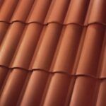 Close-up view of red clay roof tiles arranged in neat, overlapping rows, creating a textured and patterned surface.