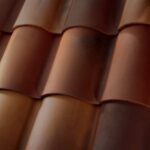 Close-up view of overlapping reddish-brown ceramic roof tiles, showing their curved, wavy pattern and smooth texture.