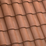 Close-up view of overlapping reddish-brown clay roof tiles arranged in a neat, repeating pattern, forming a traditional tiled roof surface.