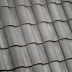 Close-up of gray ceramic roof tiles arranged in a repeating, overlapping pattern, giving the surface a textured and uniform appearance.