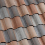 Close-up of overlapping ceramic roof tiles in alternating shades of gray and brown, arranged in a repeating wavy pattern.