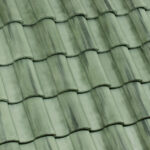 Close-up of overlapping green ceramic roof tiles arranged in a wavy, repetitive pattern with slight variations in color, giving a textured and weathered appearance.