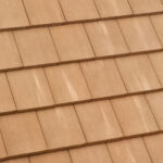 Close-up view of overlapping rows of brown roof tiles, showing their textured surface and uniform, rectangular pattern.