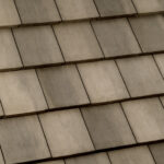 Close-up view of overlapping concrete roof shingles arranged in neat horizontal rows, displaying a uniform pattern with muted gray and beige tones.