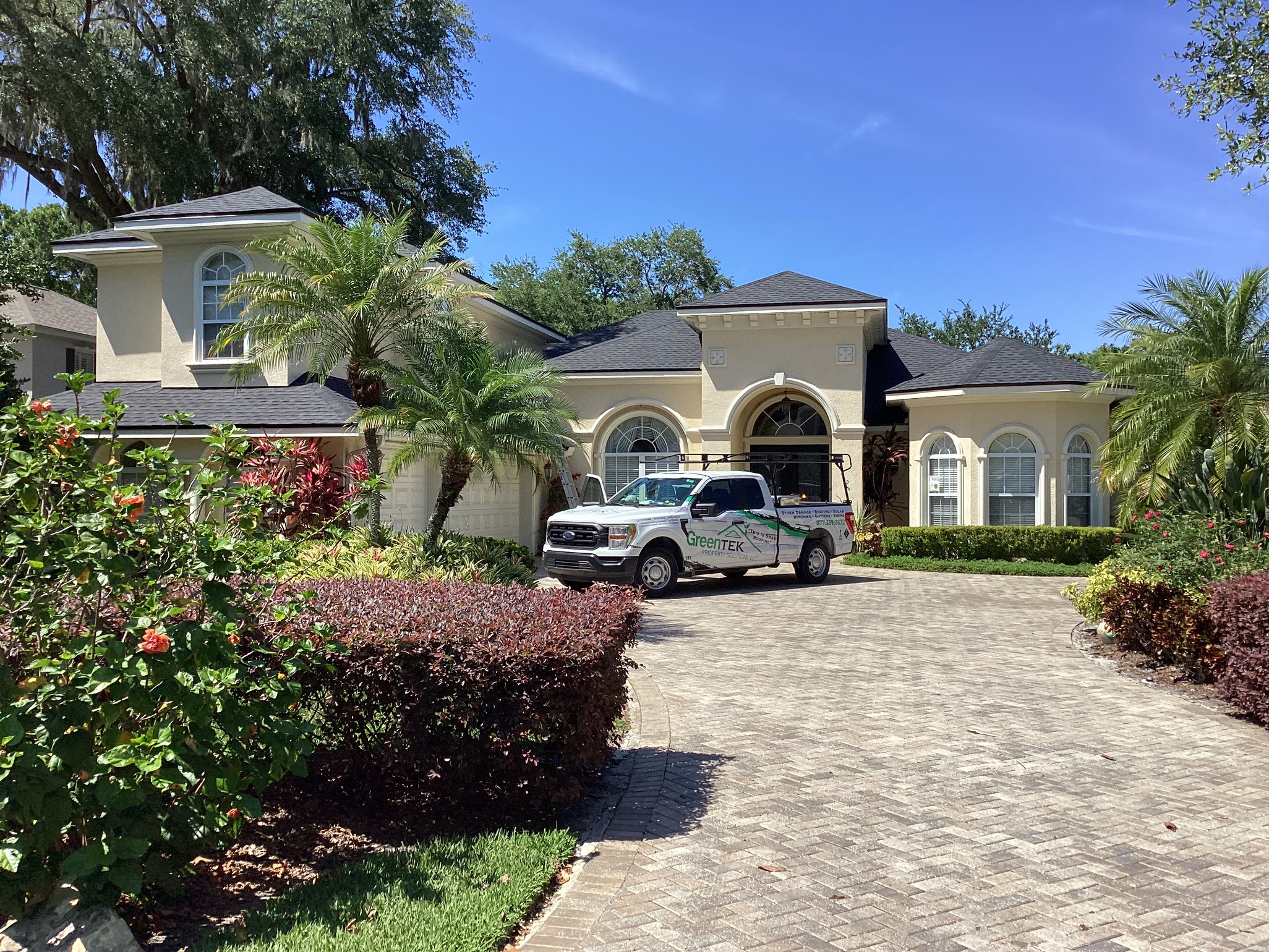 A large beige house with arched windows and palm trees, with a white pickup truck labeled "Preventex" parked in the driveway on a sunny day.